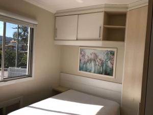 um pequeno quarto com uma cama e uma janela em Lindo Apartamento 2 Quartos 5 min da Praia de BC em Balneário Camboriú