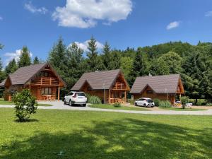 une cabane en rondins avec deux voitures garées devant elle dans l'établissement Bieszczadzka Świteź, à Baligród