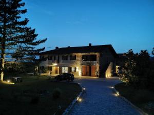 Riviera delle Langhe Wine Country House with a Pool في Monchiero: منزل في الليل مع سيارة متوقفة في الممر