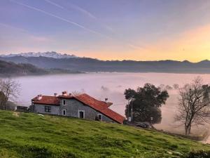 a house on top of a hill with a foggy field at Apartamentos Picabel in Cangas de Onís