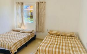 two beds sitting next to a window in a room at Gold Star Village Kitnet equipado in Majorlândia