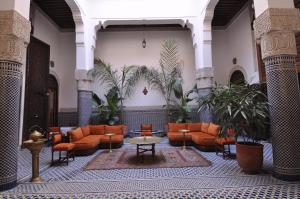 a lobby with orange furniture and potted plants at Riad Tayba in Fès