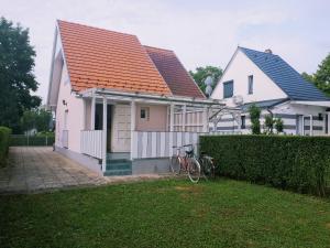 una casa blanca con techo naranja y una bicicleta estacionada en el patio en Locher Apartman 2 Bükfürdő, en Bük