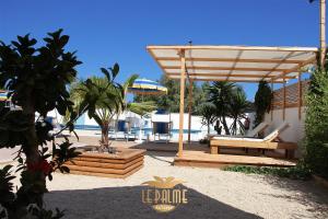 a wooden pergola with a bench and a pool at Le Palme Holidays in Palmadula