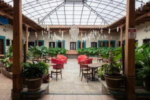 un restaurante con sillas rojas, mesas y plantas en Gran Hotel El Encanto en San Cristóbal de Las Casas