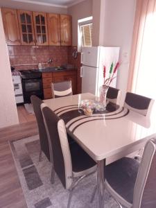 a kitchen with a white table with chairs and a white refrigerator at Apartman Dunja 2 in Bajina Bašta