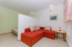 a living room with a red couch and a table at Apartments Tonci in Podgora