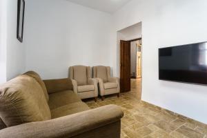 uma sala de estar com um sofá e uma televisão de ecrã plano em La Casa Rural Málaga, Caminito del Rey em Valle de Abdalagís