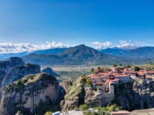 a village on a cliff with mountains in the background at The Stone Forest in Kalabaka