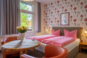 a bedroom with a bed and a table with a vase of flowers at Pension Schweizer Hof in Wernigerode