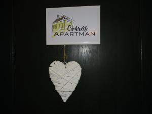 a white heart hanging on a wall with a sign at Óváros Apartman in Veszprém