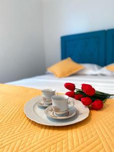 deux tasses et une assiette avec des roses rouges sur un lit dans l'établissement LoreMi apartment Pisak, à Pisak