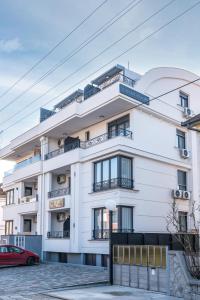 un edificio blanco con un coche rojo delante de él en Daisy resort en Novi Sad