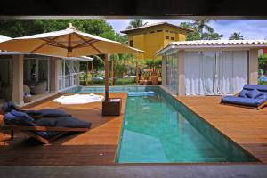 a swimming pool with a deck and an umbrella at Beach House Sauípe in Costa do Sauipe