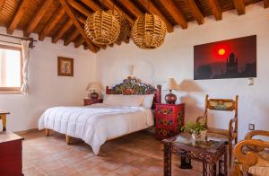 a bedroom with a large bed in a room with a table at Eco Hotel Ixhi in Pátzcuaro