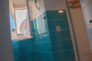 een badkamer met blauwe betegelde muren en een raam bij Cozy Dante's Apartment in Florence