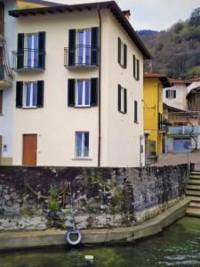 a house with a wheel on a wall next to the water at Domus Graziana in Oliveto Lario