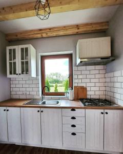a kitchen with white cabinets and a sink and a window at Domki w Bieszczadach - Apartamenty in Hoczew