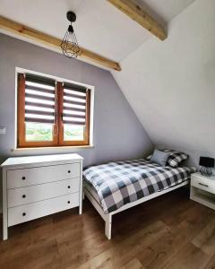 a bedroom with a bed and a dresser and a window at Domki w Bieszczadach - Apartamenty in Hoczew