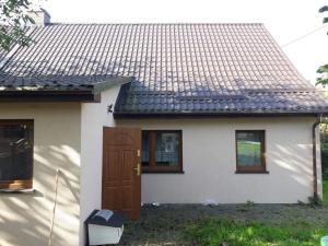 een klein wit huis met een bruine deur bij Mieszkanie dwupokojowe na wsi w domu dwurodzinnym in Postomino