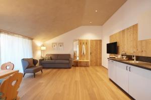 een keuken en een woonkamer met een bank en een televisie bij Ansitz Lidl in Merano