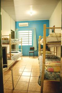 a room with three bunk beds and a chair at Pousada Bisognin in Santa Maria
