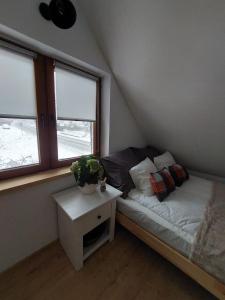 a small bedroom with a bed and a table with a plant at Chatka Podgórna in Podgórzyn