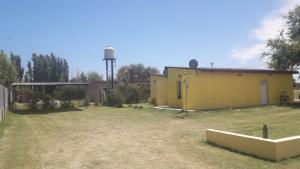 a yard with a yellow building and a water tower at Departamento Teodelina in Quehué