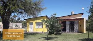a yellow house with a sign in front of it at Departamento Teodelina in Quehué
