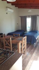 a room with two beds and a table and a kitchen at Departamento Teodelina in Quehué