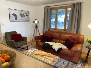 a living room with a brown leather couch and a table at Verbier One Chalet in Verbier