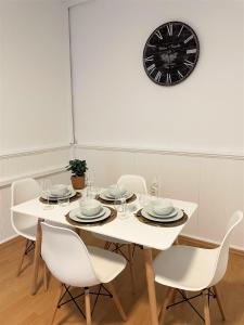 un tavolo bianco con sedie e un orologio sul muro di UrbanSuites - Dein Zuhause in Wiesbaden a Wiesbaden