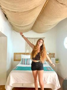 una mujer está parada frente a una cama en Hotel Club Rolling Stone, en Boca Chica