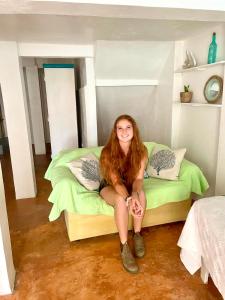 a woman sitting on a bed in a room at Hotel Club Rolling Stone in Boca Chica