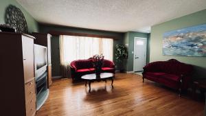 uma sala de estar com duas cadeiras vermelhas e uma mesa em Private Rooms NAIT Guest House For Men Only em Edmonton