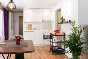 a kitchen with white cabinets and a wooden table at Spirit Apartments - Balkon - Bergsicht - Parkplatz in Engelberg