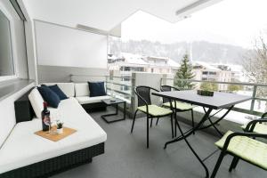 ein Wohnzimmer mit einem Sofa und einem Tisch auf dem Balkon in der Unterkunft Spirit Apartments - Balkon - Bergsicht - Parkplatz in Engelberg