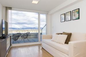 a living room with a couch and a large window at Pacifico Departamentos in Ushuaia
