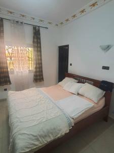 a large bed in a bedroom with a window at PN Meublés FULL OPTION Odza Dispose d'une voiture et un chauffeur gratuitement de l,aéroport aux appartements pour des réservations minimum de 7 jours in Yaoundé