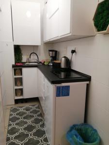 a small kitchen with white cabinets and a black counter top at Przy rynku in Duszniki Zdrój