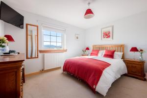 1 dormitorio con 1 cama roja y blanca y TV en Tornapress, en Muir of Ord