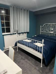 a bedroom with a white bed and a blue wall at White Rose Hotel and Restaurant in Leeds