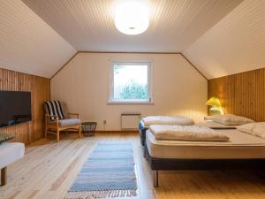 1 dormitorio con 2 camas, TV y silla en Holiday home Fanø CXXVIII, en Fanø