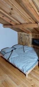 a bed in a room with a wooden ceiling at CHALET BORŮVKA - biofarma na samotě v lesích in Pavlov