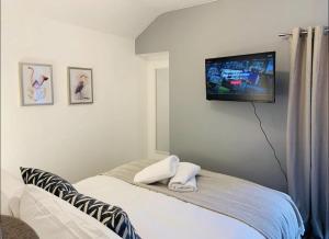 a bedroom with a bed with a tv on the wall at 4 Bed Executive Style House - Near City Centre in Swansea