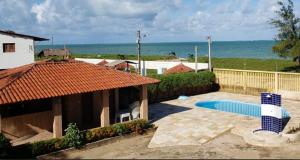 a house with a swimming pool next to the ocean at Casa Logan - Condomínio Village, Casa 15 in Maragogi