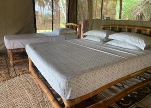 2 Einzelbetten in einem Zimmer mit Fenster in der Unterkunft Natura Luxury Lake Hut in Ouidah