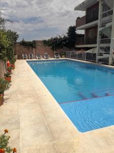 a large blue swimming pool with chairs in front of a building at Altos del Plata in Villa Carlos Paz