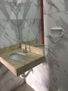 a bathroom with a marble sink and a mirror at Hotel Kolosso in Aragarças