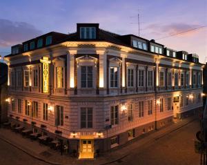 un gran edificio blanco con luces encendidas por la noche en Hotel Concordia, en Lund